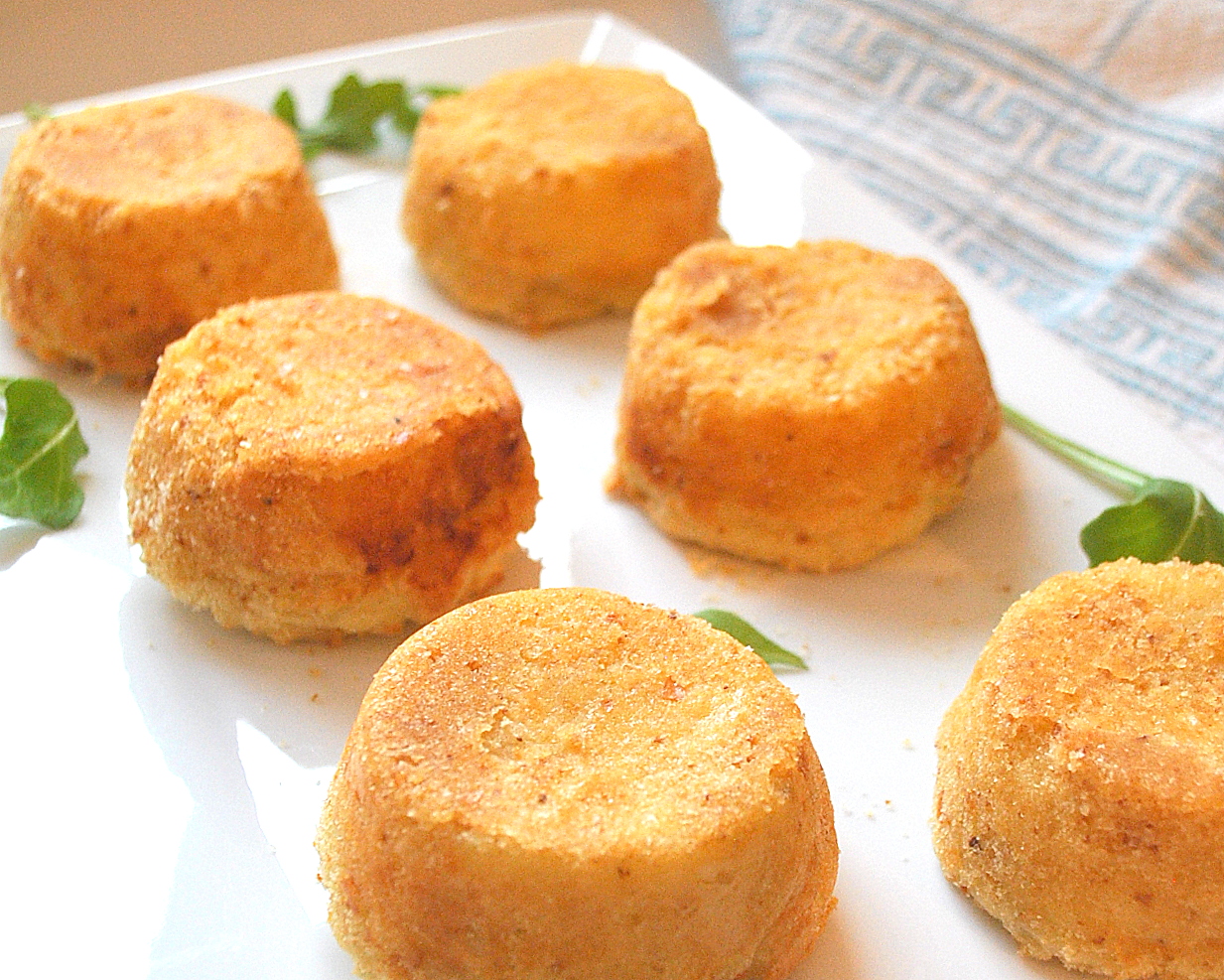 Mashed Potato Cakes (aka Croquettes) Mashed Potato Cakes ( croquettes) served on a white platter.