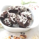 White bowl filled with chocolate covered dates with shredded coconut scattered on top.