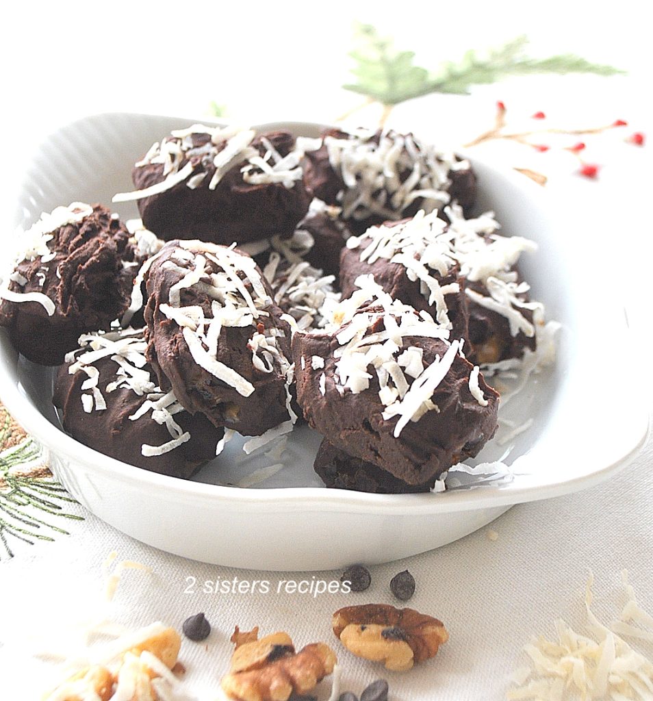 White bowl filled with chocolate covered dates with shredded coconut scattered on top.