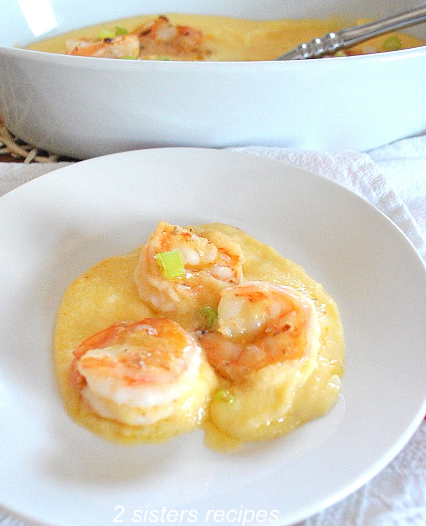 A white plate with a serving of shrimp and polenta. by 2sistersrecipes.com