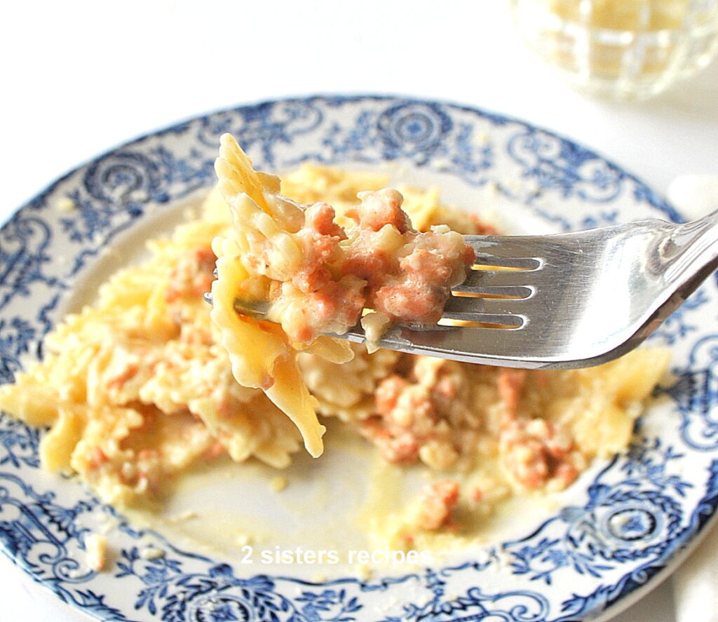 A forkful of farfalle pasta with bits of smoked salmon cream sauce.
