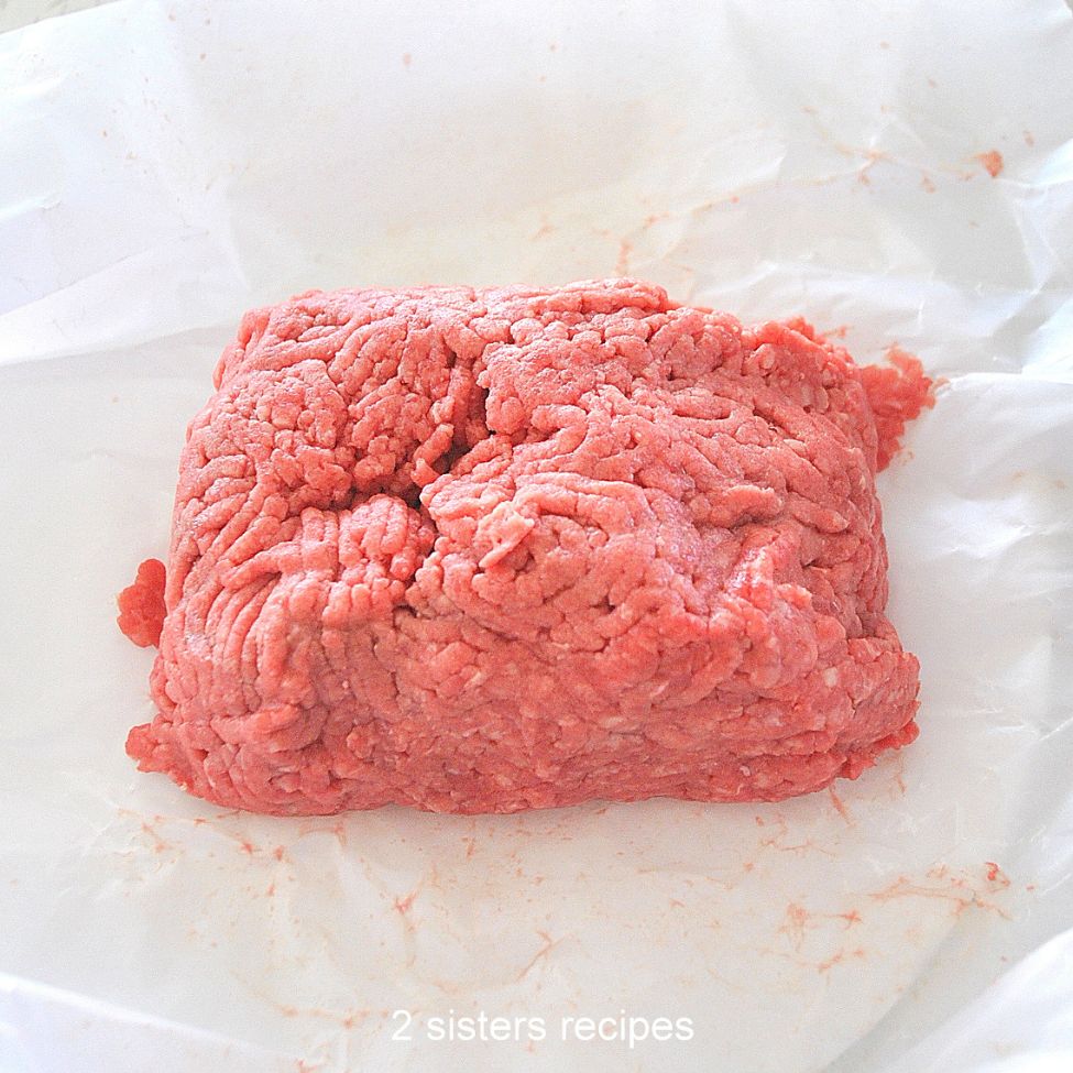 About 1 pound of raw ground beef on a white parchment paper. 