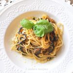 A white bowl filled with spaghetti and zucchini with fresh basil on top.