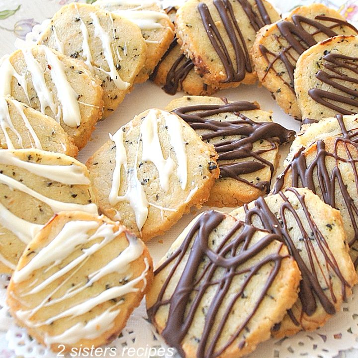 A white plate filled with shortbread cookies drizzled with white and dark chocolate on top.