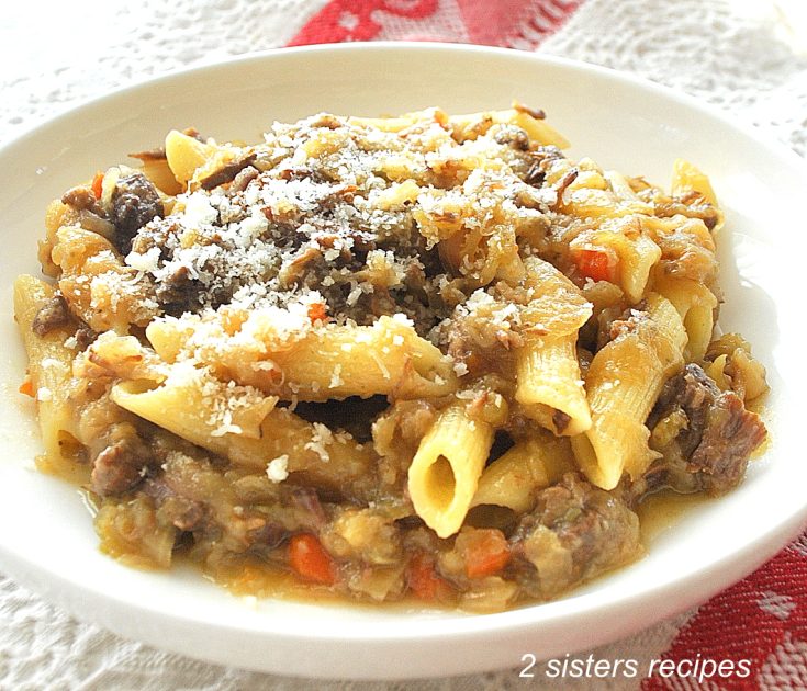 A bowl of penne pasta with onions and meat sauce on top.
