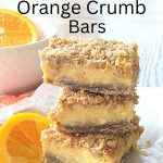 Three orange crumb bars are piled on top of one another and served on a white plate. A slice of an orange on the side.