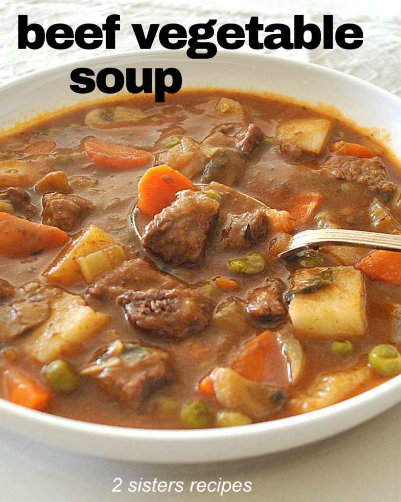 A spoonful of beef vegetable soup in a white bowl. 