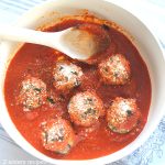 A sauce pot filled with tomato sauce and eggplant meatballs.