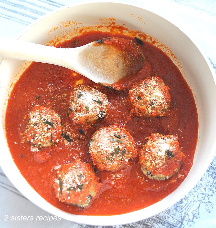 A sauce pot filled with tomato sauce and eggplant meatballs. by 2sistersrecipes.com