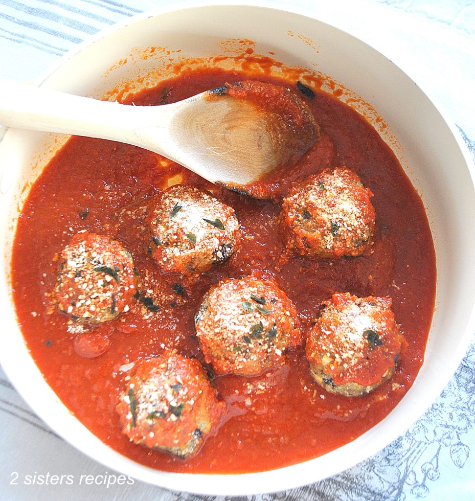 A sauce pot filled with tomato sauce and eggplant meatballs.