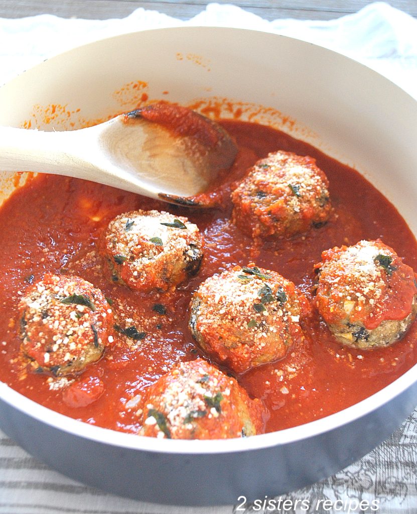 A blue pot with tomato sauce, wooden spoon and eggplant meatballs. by 2sistersrecipes.com