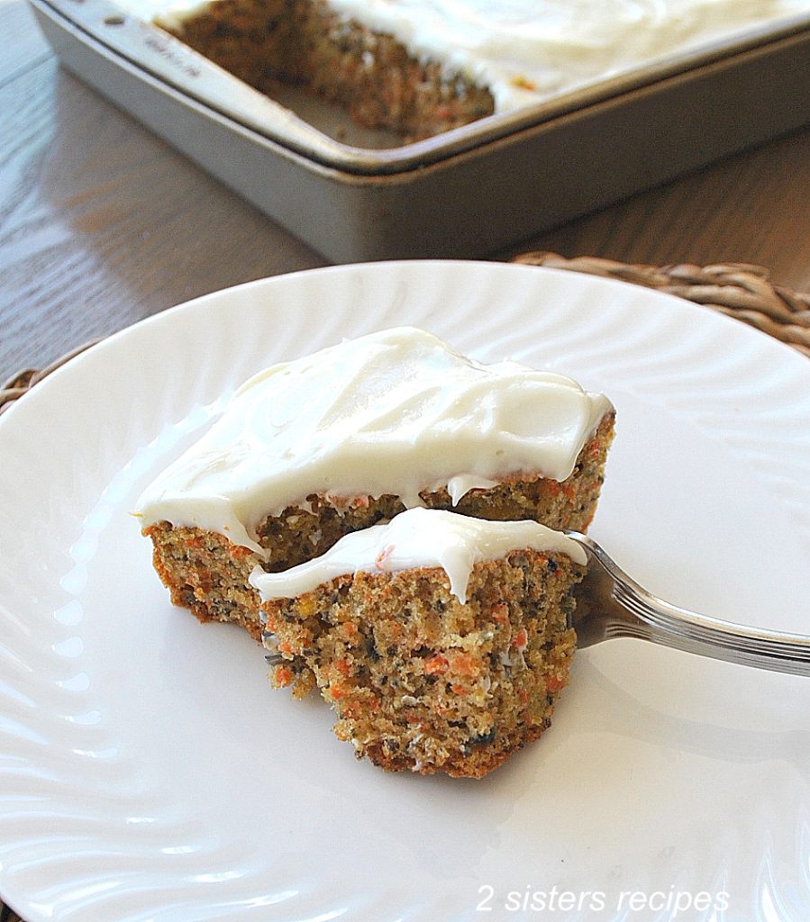 A fork is cutting through a piece of carrot cake. by 2sistersrecipes.com