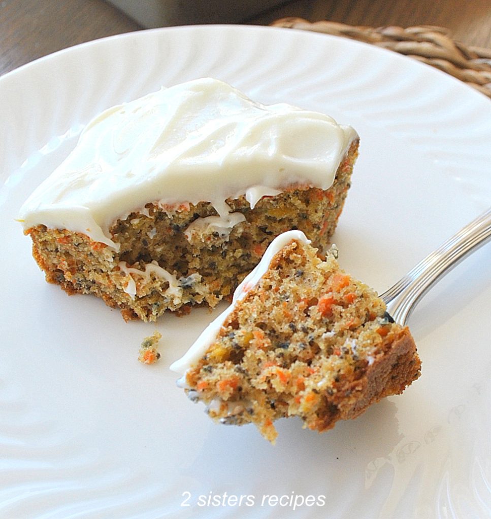A forkful of carrot cake with frosting on top. by 2sistersrecipes.com