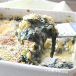 A serving of a creamy spinach gratin from a white baking square dish.