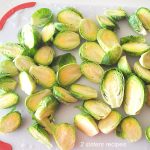 A white board filled with cleaned and prepped fresh Brussels Sprouts.