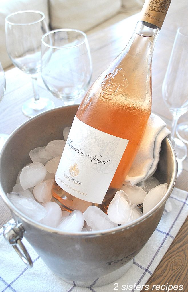 A bottle of Rose' wine in a bucket filled with ice. by 2sistersrecipes.com