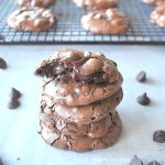 A pile of chocolate cookies with one on top is broken in halve.