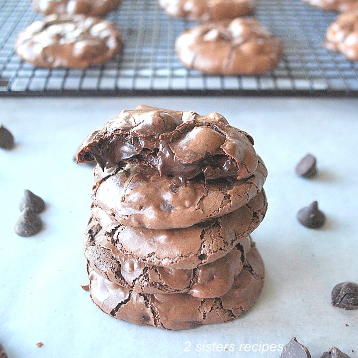 A pile of chocolate cookies with one on top is broken in halve.