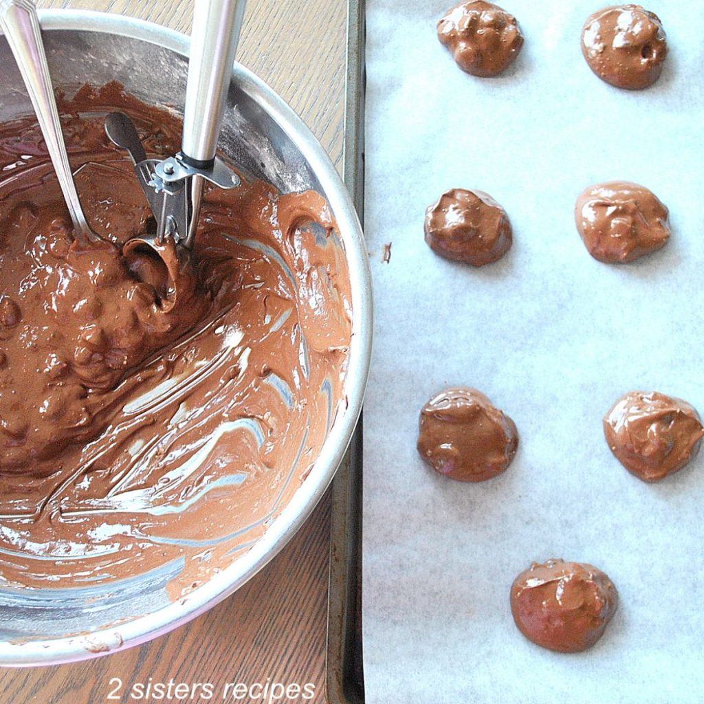 A large mixing bowl with chocolate fudge cookie batter, and a cookie sheet with raw cookie dough on it. by 2sistersrecipes.com