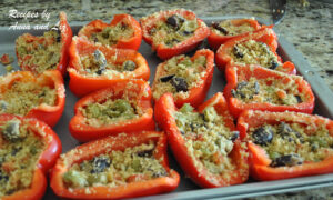 Red bell peppers sliced in halves and stuffed on a baking sheet.