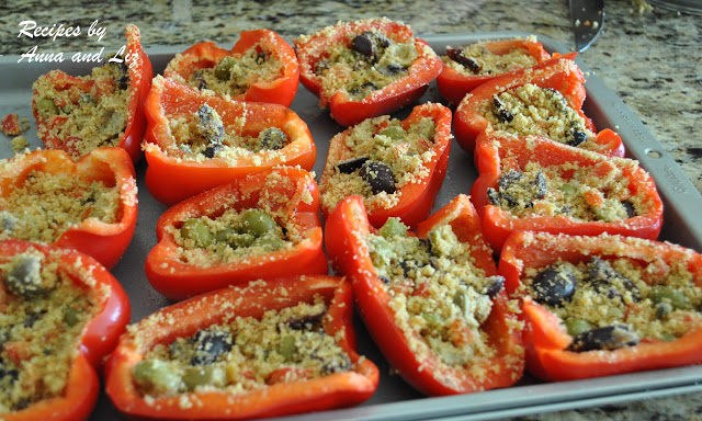 Red bell peppers sliced in halves and stuffed on a baking sheet.