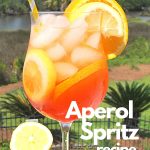A tall wine glass filled with ice cubes, slices of lemon and orange, Aperol liqueur.