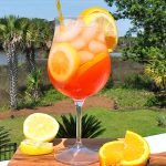 A cocktail glass filled with ice cubes and an orange liqueur, with lemon and orange slices.