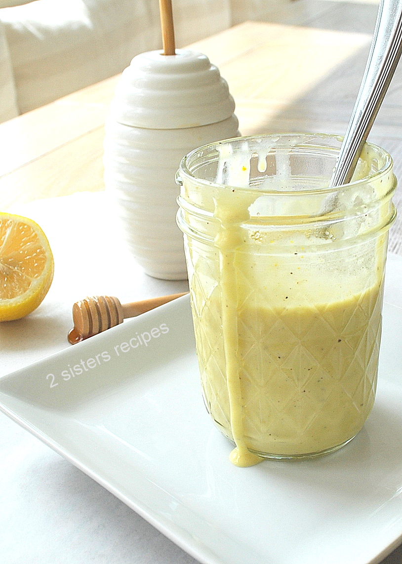 A small mason jar with honey mustard dressing and a spoon inside.