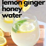 A glass of lemon ginger water on a wood board.