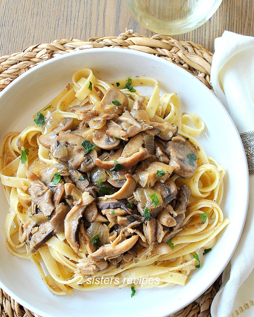 A white dish filled with fettuccini pasta topped with a mushroom sauce.