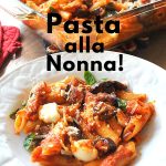 A white plate with penne pasta tossed with tomato sauce and roasted cubed eggplant, and topped with chunks of mozzarella.