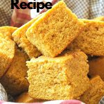 A basket filled with square pieces of pumpkin cornbread.