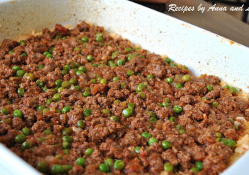 a large white casserole dish with meat and peas mixture. by 2sistersrecipes.com