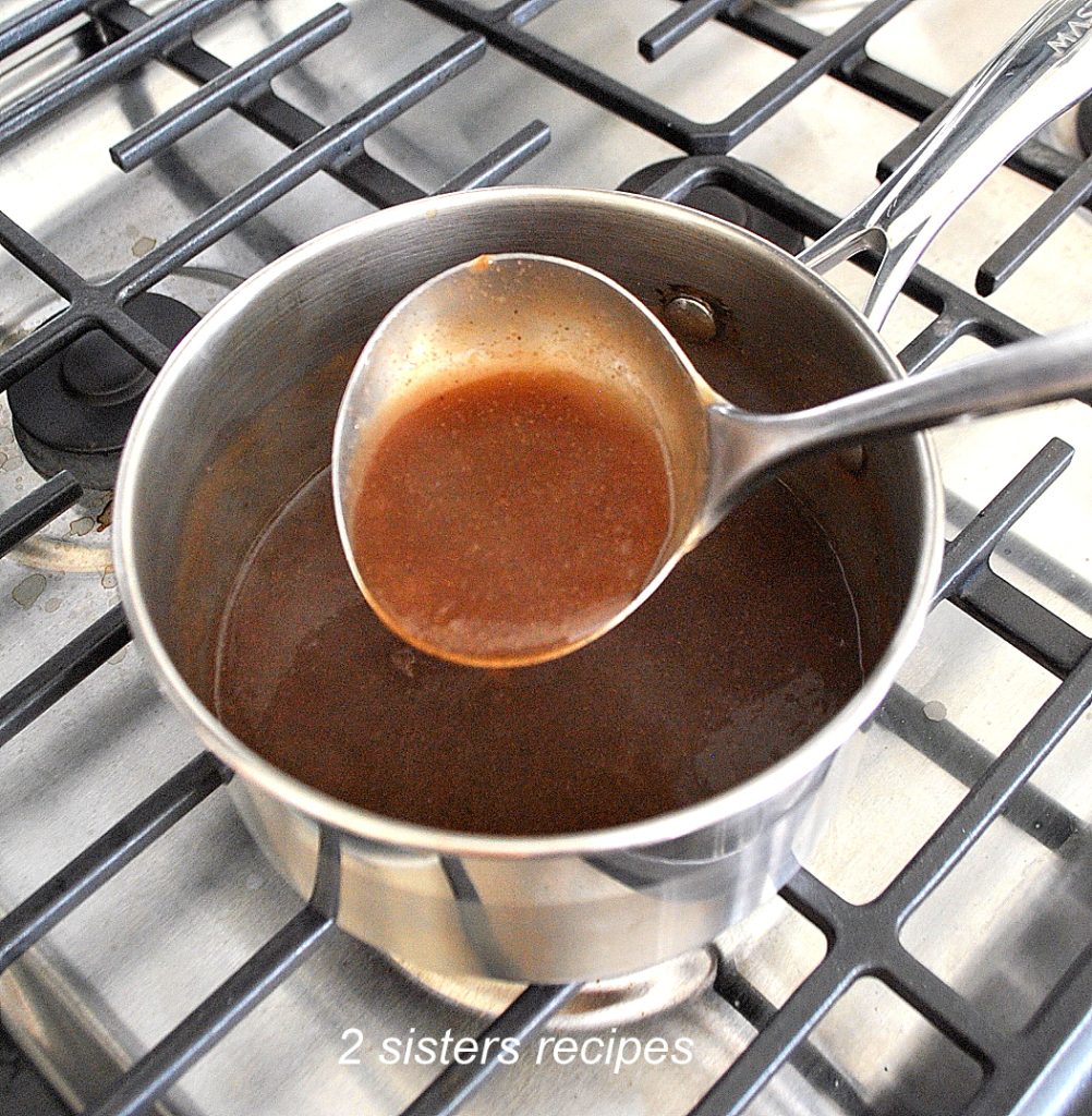 A small pot filled with brown gravy and a ladle loaded with gravy.