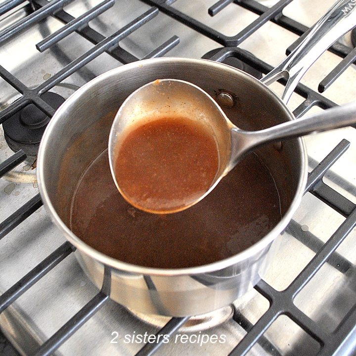 A small pot filled with brown gravy and a ladle loaded with gravy.