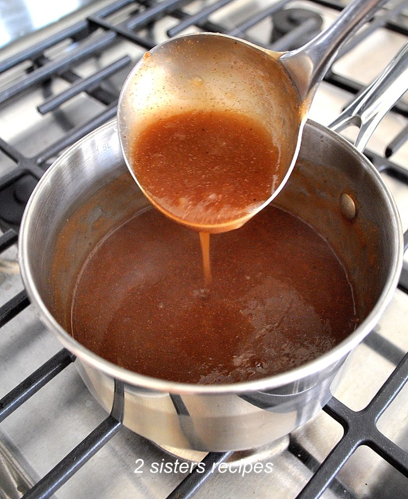 A ladle pouring some brown gravy back into a sauce pan. by 2sistersrecipes.com