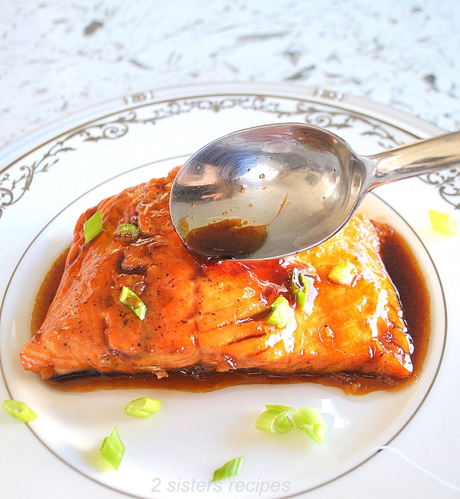 Spooning the maple glaze over the salmon. by 2sistersrecipes.com