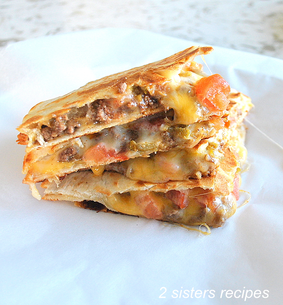 A loaded quesadilla cut into triangle pieces piled and served on a white plate.