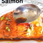 Cooked salmon with a glaze poured over it served on a dinner plate.