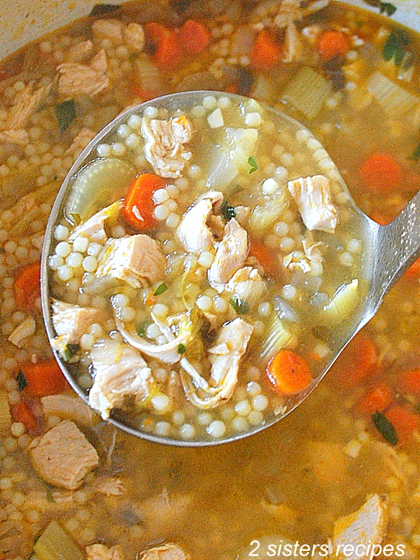 A ladle loaded with homemade chicken soup.