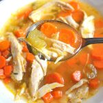 A spoonful of turkey soup with carrots.