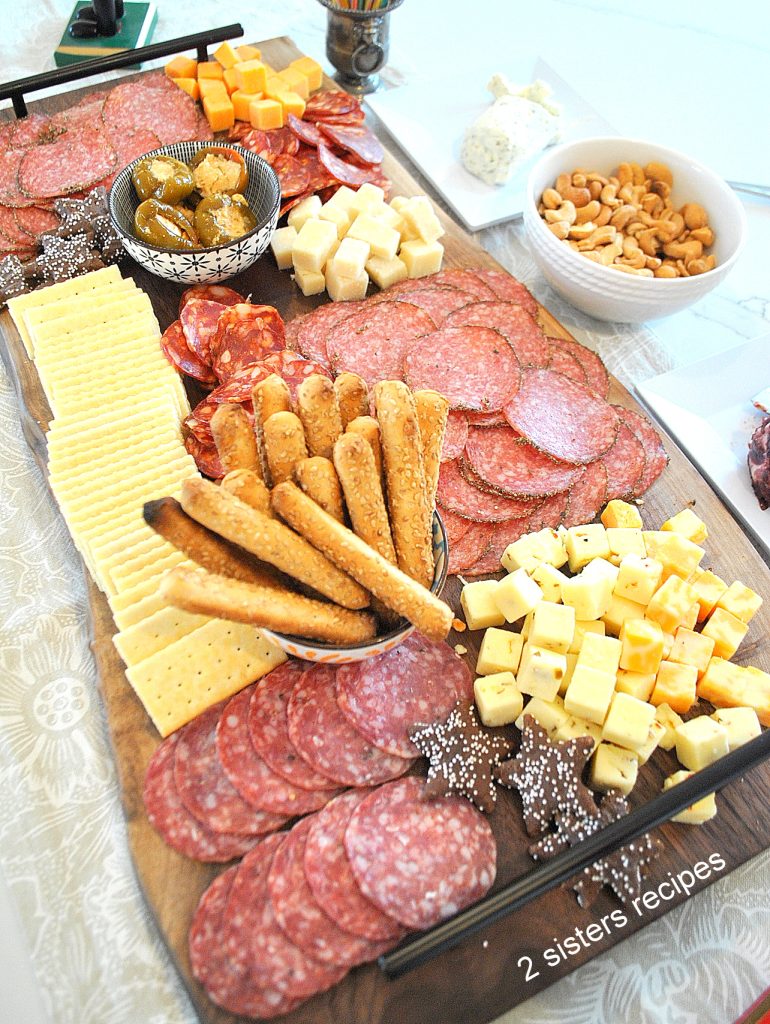 A large charcuterie board filled with cured meats, cheeses and crackers. by 2sistersrecipes.com