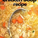 A pot filled with chicken soup, chopped carrots and little pasta.