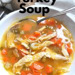 A large white bowl filled with soup, loaded with carrots and turkey meat.