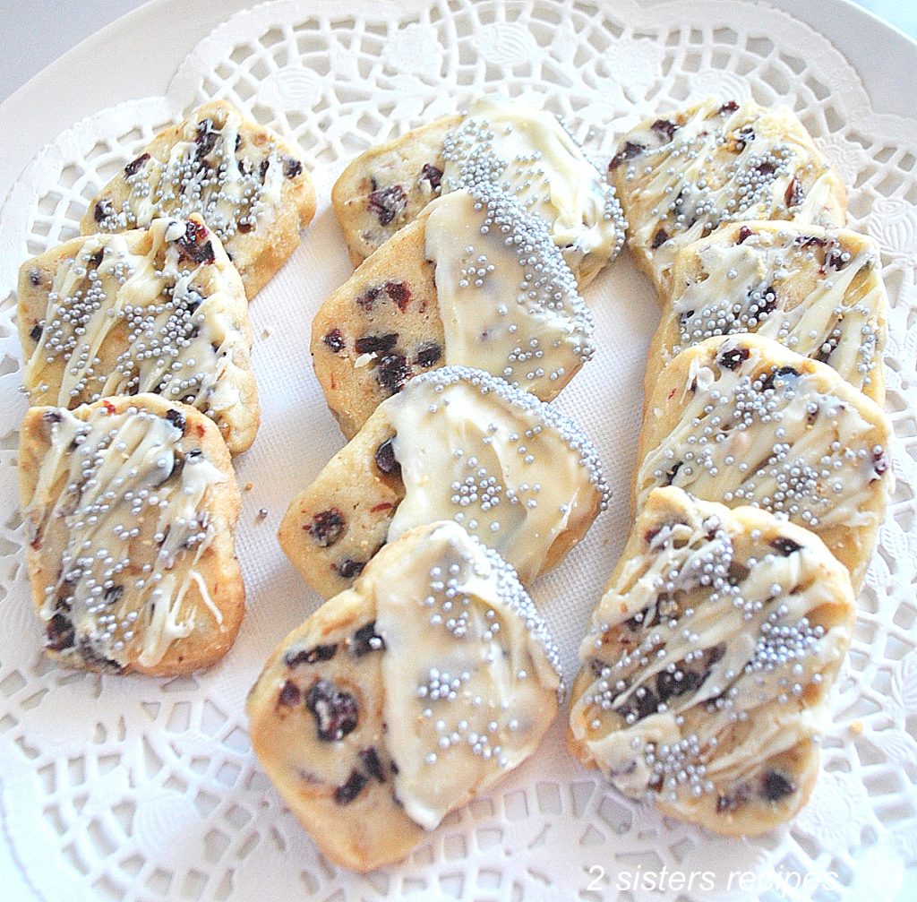 A plate filled with cranberry butter cookies on a white doily.