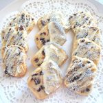 A plate filled with cranberry butter cookies on a white doily.