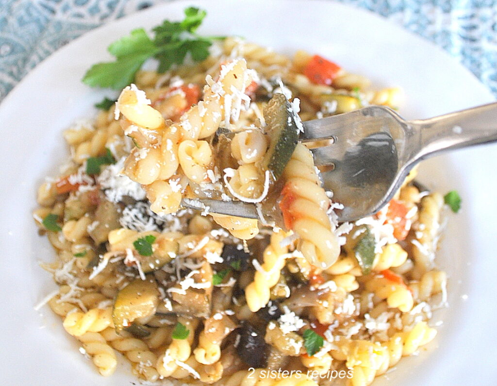 A forkful of curly pasta with fresh sauteed vegetables.