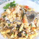 A forkful of curly pasta with fresh sauteed vegetables.