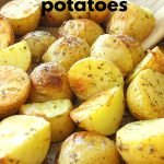 A baking dish with roasted crispy potatoes with a wooden spoon.