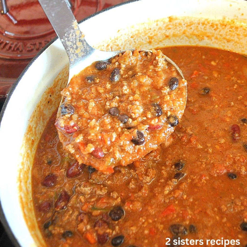 A large Dutch oven pot with a ladle full of chili bean stew.